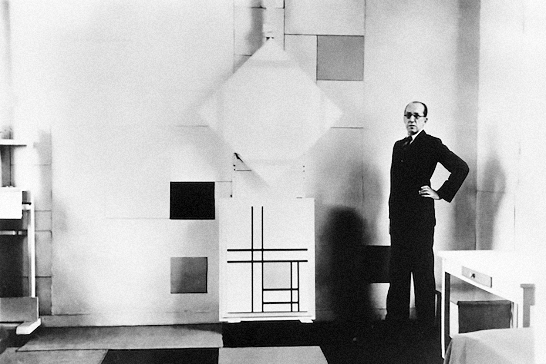 Piet Mondrian in his studio with (top) Lozenge Composition with Four Yellow Lines (1933) and (bottom) Composition with Double Lines and Yellow (1934), Paris, October 1933. © Charles Karsten via Het Nieuwe Instituut.