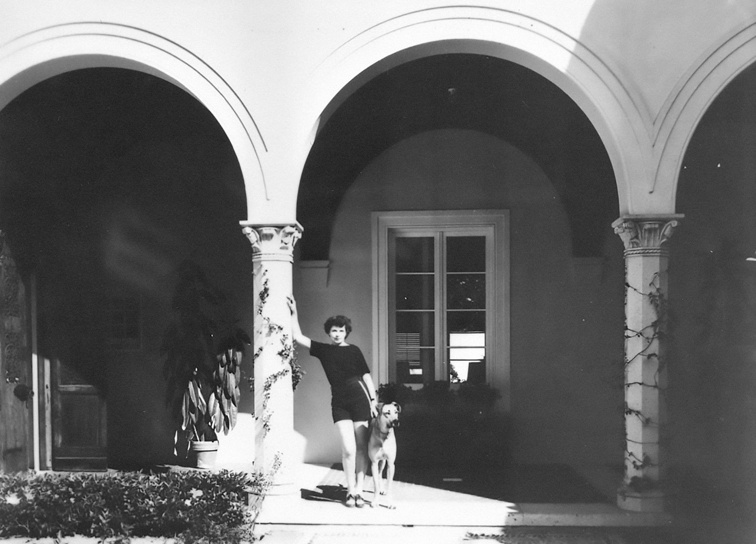 Emily von Romberg with a dog in the entrance courtyard with the coat of arms of the von Romberg family recreated with pebbles, “Brünninghausen,” Montecito, California